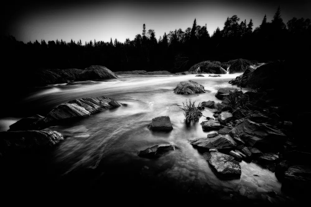 Indian River running white over dark rocks below the falls, spruce against the evening sky.